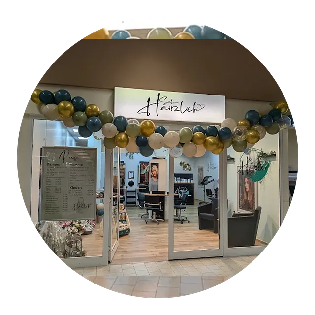 Der Eingang von Salon Hairzlich in der Frontansicht. Es hängen goldene, weiße und schwarze Ballons in einer langen Kette von links nach rechts über dem Eingang. 